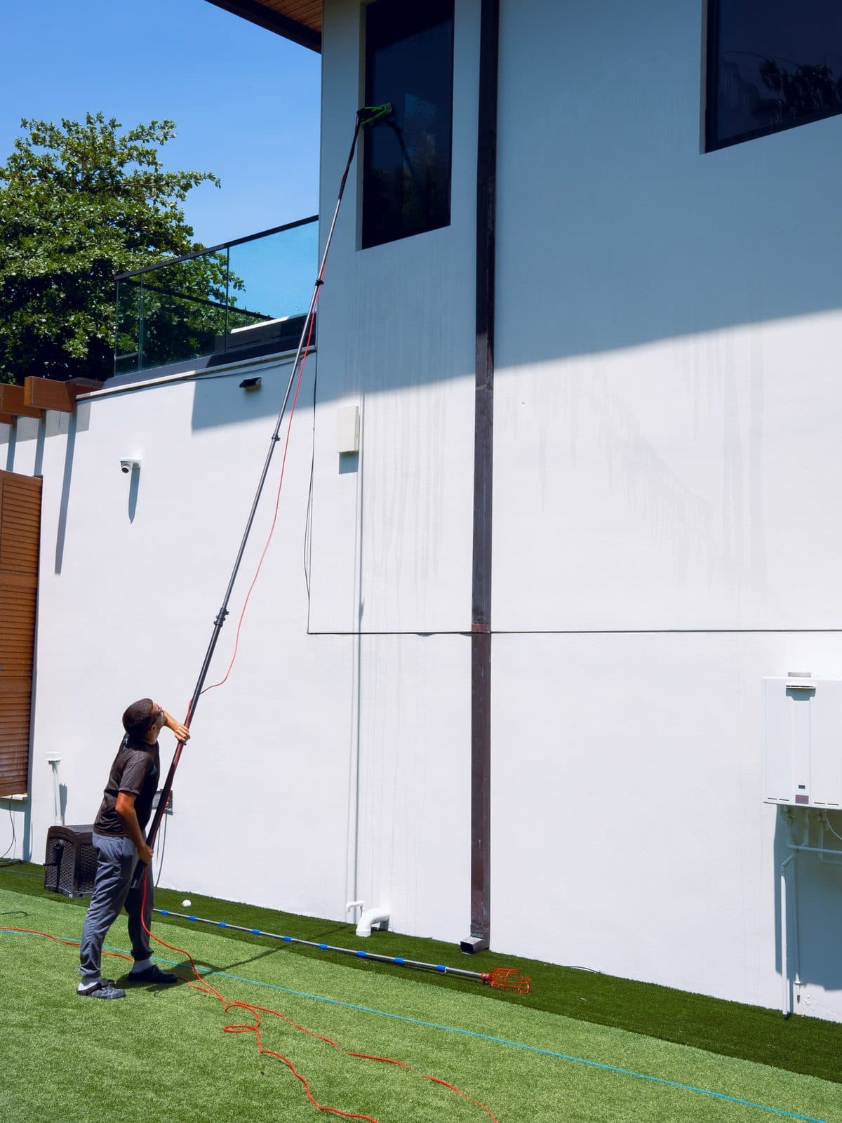 Water-fed pole cleaning tall exterior windows on a Florida home