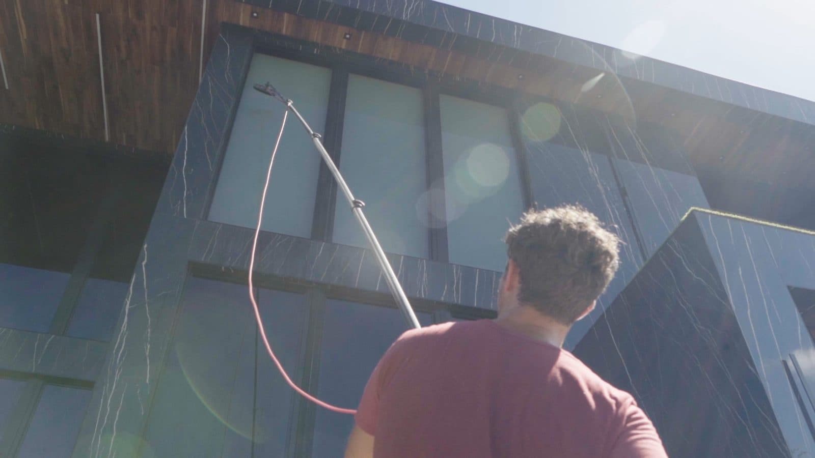 Fresh Frames technician cleaning a large picture window on a modern Florida home